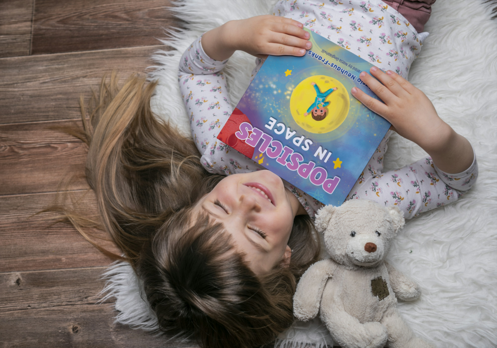 Child laying down and holding book.